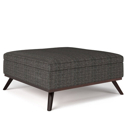 The Owen Multifunctional Square Coffee Table Storage Ottoman features dark gray textured upholstery, slim angled wooden legs, and a modern minimalist design.
