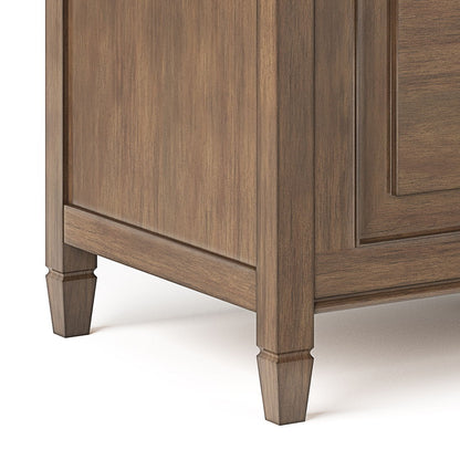 Close-up of the Connaught - Handcrafted Storage Bench Trunk’s lower corner highlights its panel-style detailing, tapered legs, and warm brown wood grain finish.