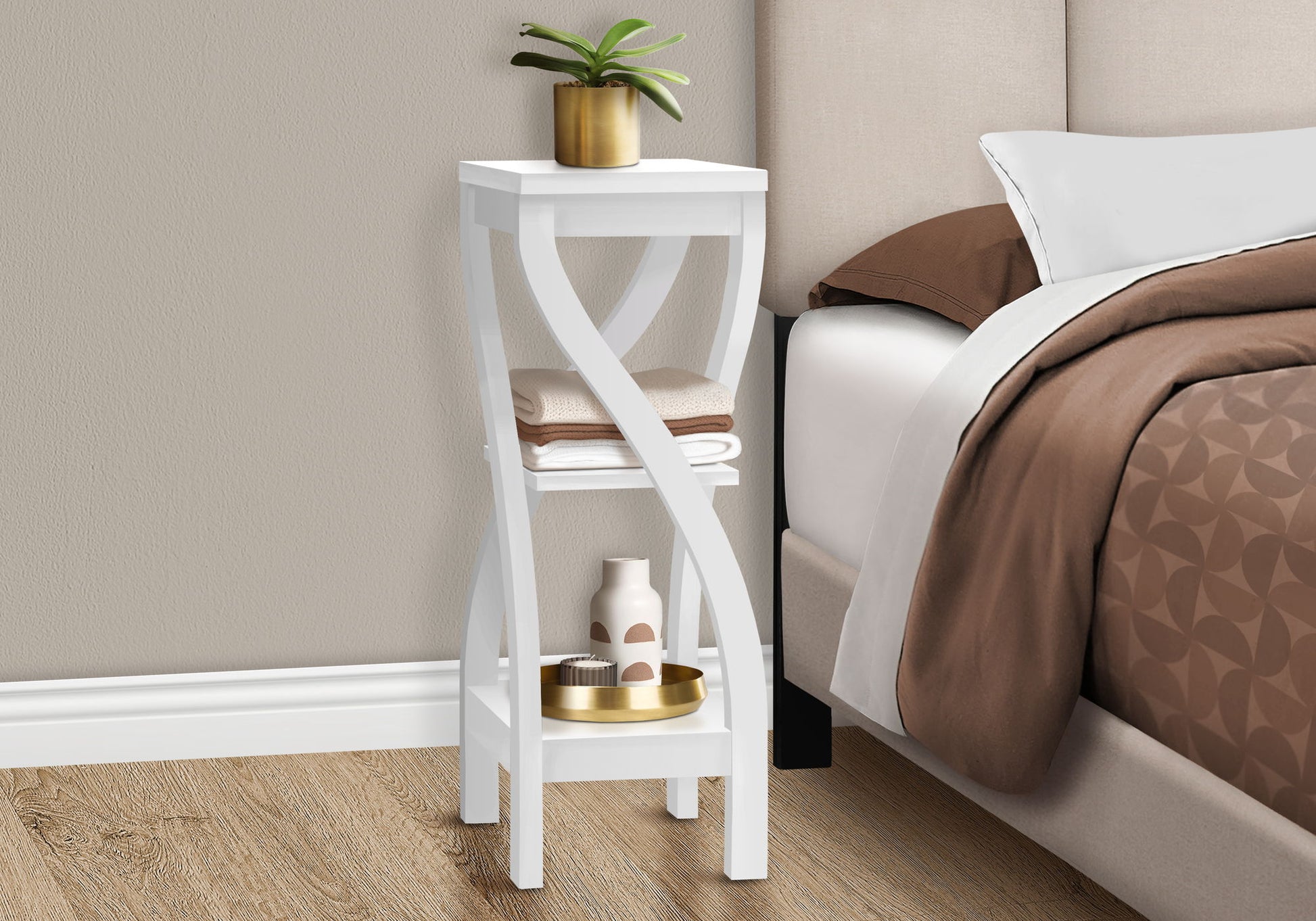 A square white Accent Table with curved legs stands beside the bed. Featuring contemporary modern style, it holds a potted plant, towels, and decor atop brown and white bedding.