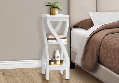 A square white Accent Table with curved legs stands beside the bed. Featuring contemporary modern style, it holds a potted plant, towels, and decor atop brown and white bedding.