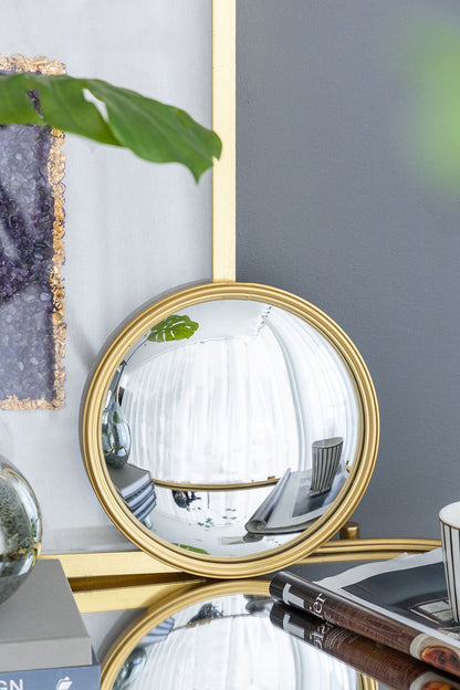 A Round Mirror, Circle Mirror With Iron Frame For Living Room Bedroom Vanity Entryway Hallway sits on a tabletop reflecting white curtains and a chair, with books, a cup, and plant nearby; the backdrop features a gray wall and geode-detail framed art.
