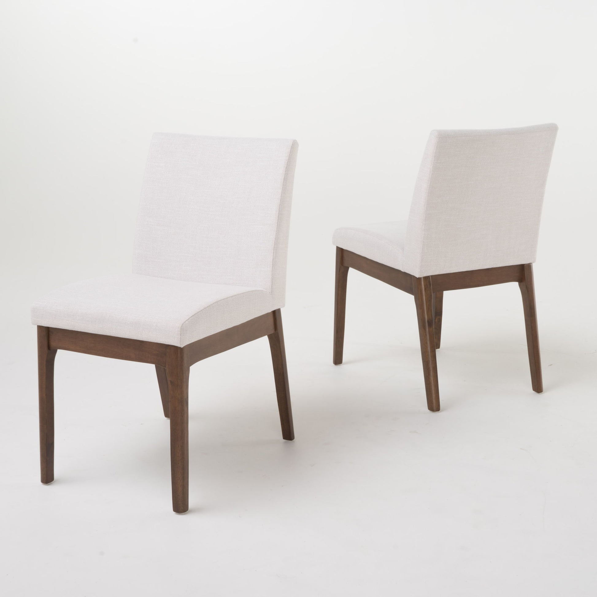 A pair of Contemporary Fabric Comfort Dining Chairs (Set of 2) with light beige upholstered seats and backs, supported by dark wooden frames, are displayed on a plain white background—one faces forward, the other backward.