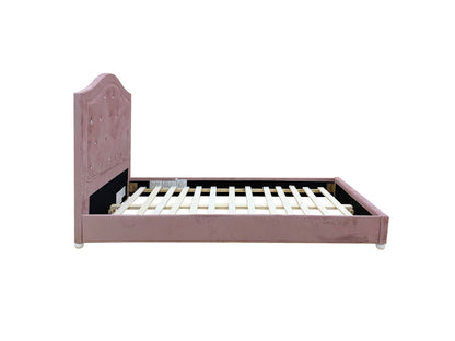 The Reggie Twin Bed in pink features an upholstered frame with a tufted, curved headboard and sturdy wooden slats, shown against a plain white background.