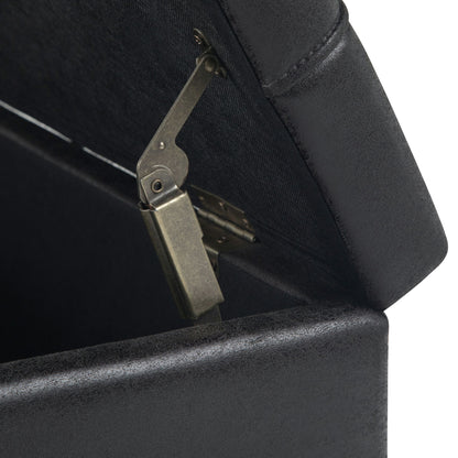 Close-up of a metal hinge holding open the lid of the Harrison Upholstered Coffee Table Storage Ottoman, showing part of its padded black lid and interior edge.