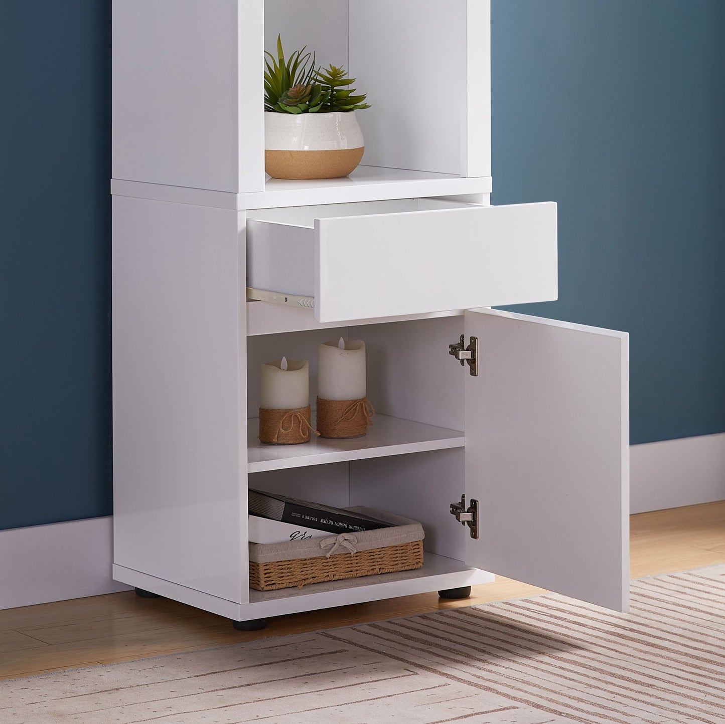The Modern Wine Showcasing Cabinet with two glass shelves and storage cabinet features an open drawer, open lower door revealing shelves with candles, a woven basket, books, and a potted succulent on the upper shelf.