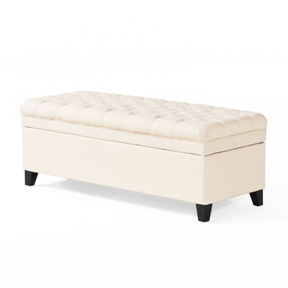 The Juliana Storage Ottoman features a beige tufted cushioned top and short black birch legs, shown against a plain white background.
