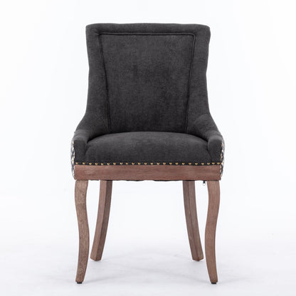 The Ultra Side Dining Chair set features thickened dark gray fabric, a high back, neutrally toned solid wood legs, and bronze nail head trim along the seat edge, displayed against a plain white background.