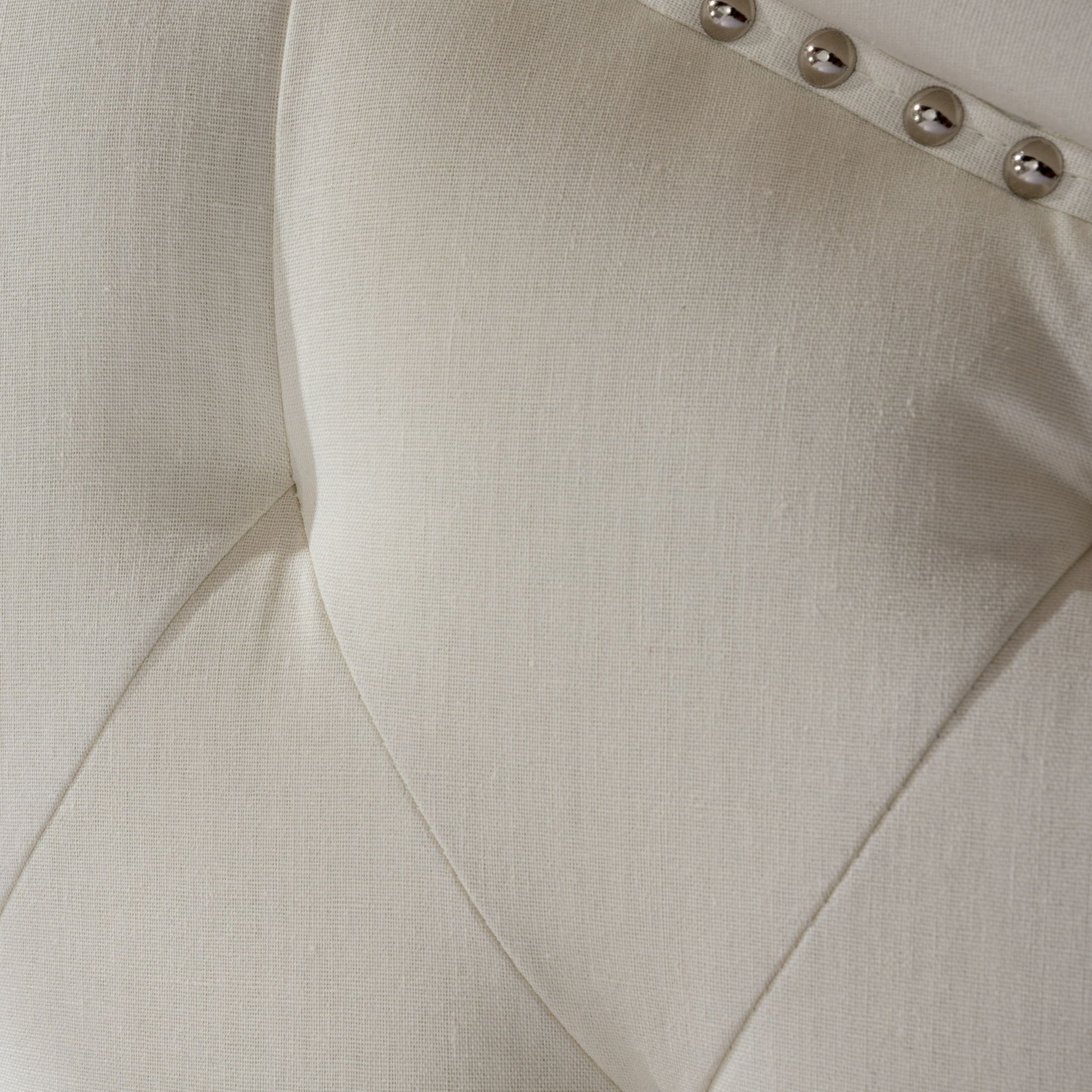 Close-up of the Kaarina Contemporary Tufted Fabric Headboard, showcasing its cream upholstery with button-tufted stitching and a row of metallic decorative studs along the edge.
