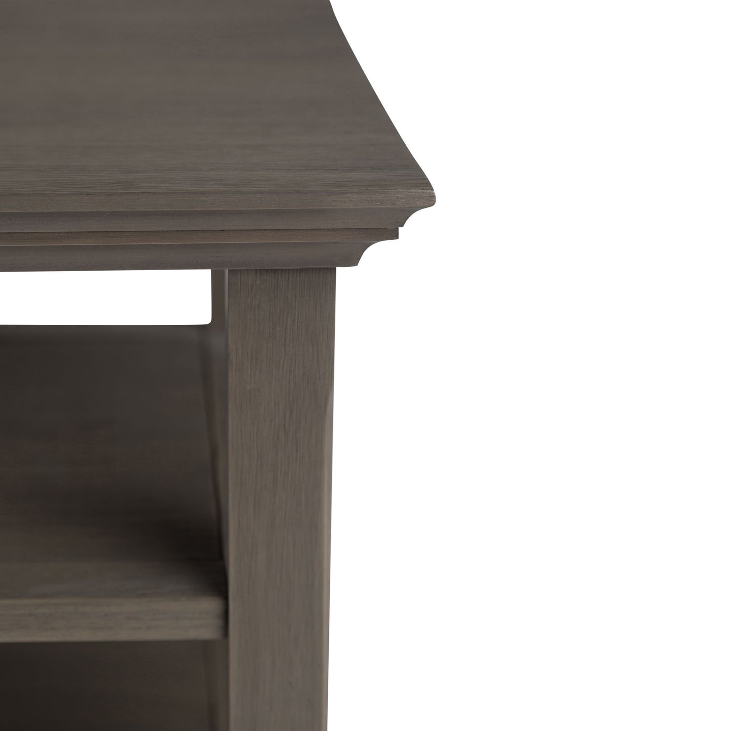 Close-up of the Acadian - Handcrafted End Table corner highlights its decorative edge, shelf below, and grayish-brown finish, focusing on exquisite craftsmanship and only part of the table.