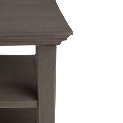 Close-up of the Acadian - Handcrafted End Table corner highlights its decorative edge, shelf below, and grayish-brown finish, focusing on exquisite craftsmanship and only part of the table.
