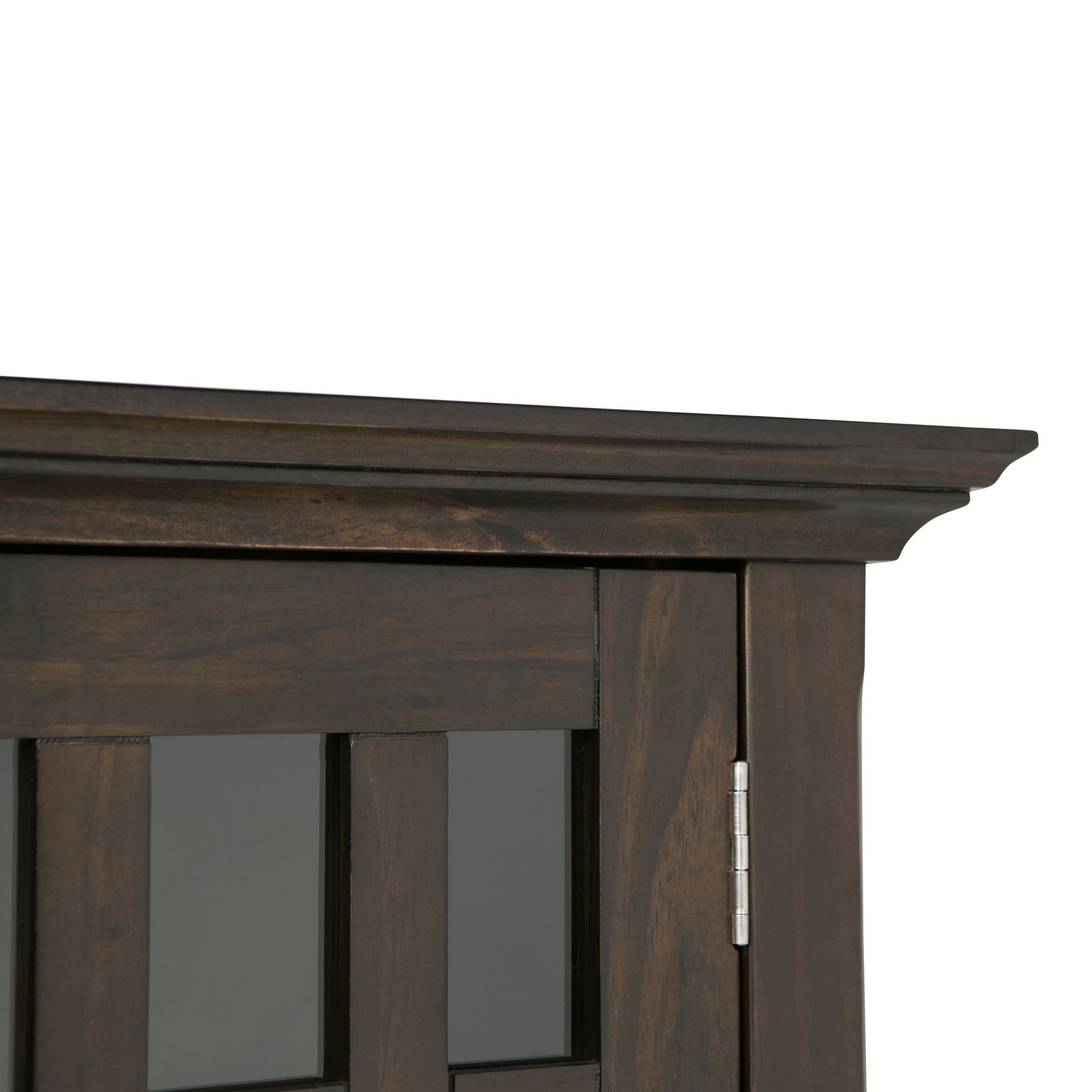 Close-up of the top corner of the Bedford - Storage Media Cabinet, featuring dark wood, crown molding detail, a glass panel door, and a visible metal hinge on the right side.