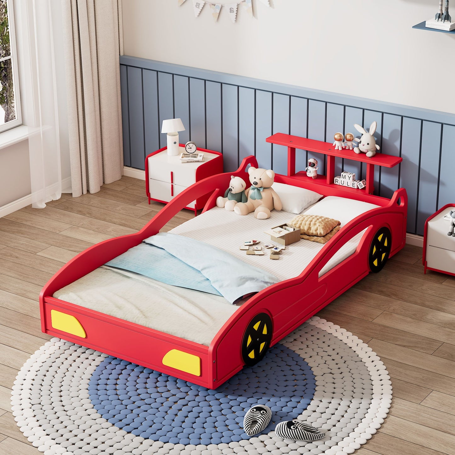 A child’s bedroom with a Wooden Race Car Bed (Car Shaped Platform Twin Bed With Wheels For Teens), blue and white bedding, stuffed animals on the headboard shelf, toys on a round rug, light wood floors, and blue paneled walls.