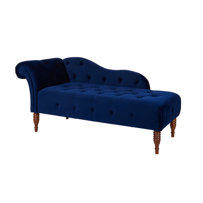 The Samuel Tufted Roll Arm Chaise Lounge features blue velvet upholstery, wooden legs, a curved backrest on one side, and button-tufted detailing on the seat and back, displayed against a white background.
