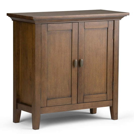 The Redmond Handcrafted Low Storage Cabinet features a smooth wooden finish, two paneled doors with metal handles, and four short legs—offering simple, classic style for storage in living rooms or hallways.