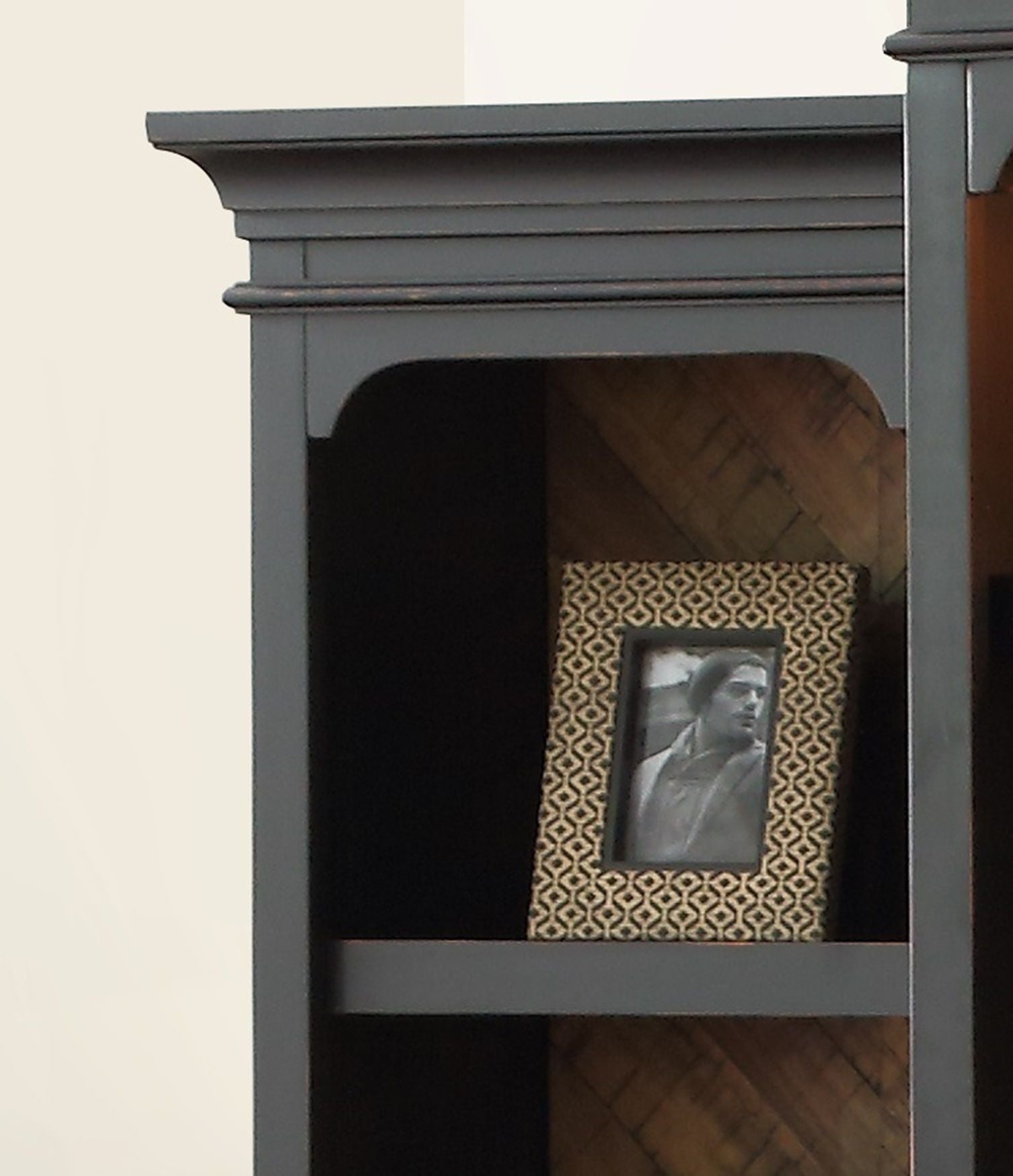 A close-up of a dark wooden shelf displays the Brighton - Pier frame with a geometric pattern, holding a black-and-white photo; the shelf background is a partially light-colored wall.