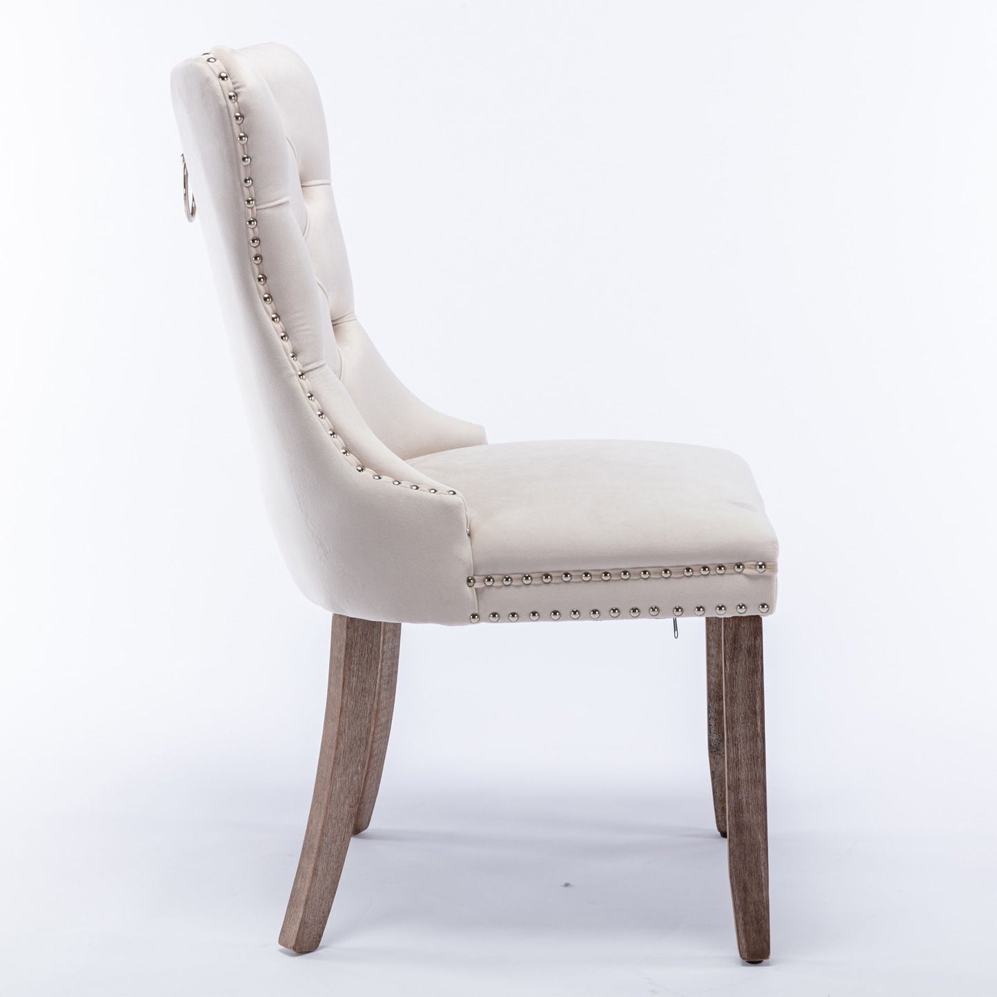 Side view of the Nikki modern high-end tufted velvet dining chair with solid wood legs, nailhead trim, and metal ring handle on the backrest, shown in beige against a plain white background.
