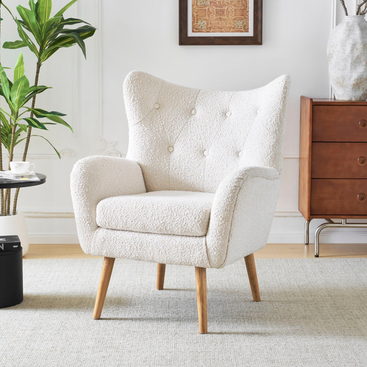 The Mid-Century Modern Arm Chair with wingback design and wood legs is featured on a light rug in a stylish living room, next to a wooden dresser, potted plant, and round side table holding a teacup.