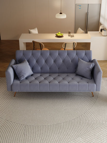 A modern living room features a Convertible Double Folding Living Room Sofa Bed in blue-gray with two cushions on a textured circular rug. Behind it, there’s a dining table with chairs, a hanging light, and a refrigerator.