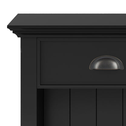 Close-up of the top corner of the Acadian - Bedside Table, Handcrafted, in black wood. Features a drawer with a dark metal cup pull handle and vertical panel detailing below.