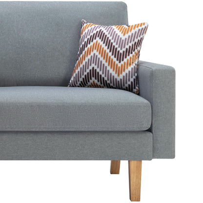 The Bahamas - Minimalistic Sofa With 2 Throw Pillows is a modern light gray sofa with wooden legs, shown in profile, featuring a decorative pillow with an orange, brown, and gray zigzag pattern against the armrest.