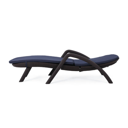 The Mikael - Chaise Lounge With Cushion is a modern outdoor chair with a dark woven frame, curved legs, and sleek design, featuring navy blue cushioned seat and backrest for contemporary style.