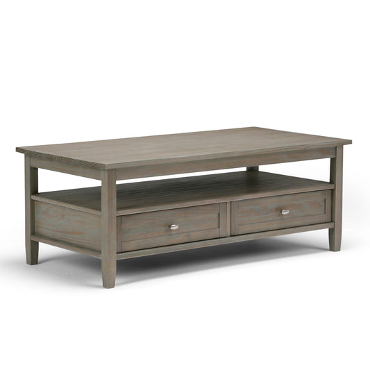 The Warm Shaker - Handcrafted Table is a rectangular wooden coffee table with a gray finish, two drawers with metal knobs, and an open shelf beneath the tabletop.