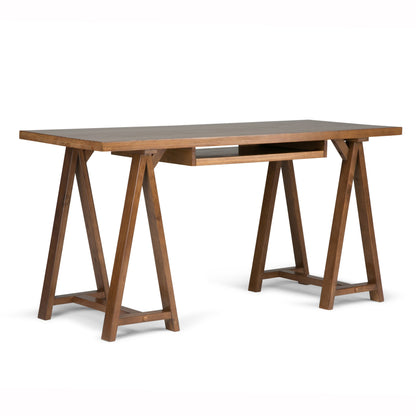 The Sawhorse - Handcrafted Desk features a rectangular wooden top, one central drawer, and two trestle-style legs per side joined by horizontal supports. It has a medium brown finish.