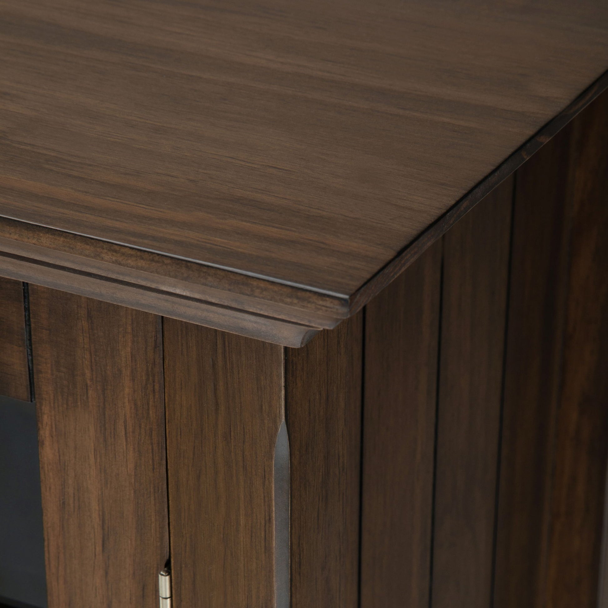 Close-up of the top and corner of the Bedford - Storage Media Cabinet, featuring its dark brown finish, visible wood grain, and detailed panel design.