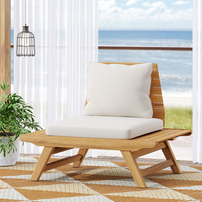 The Sedona Outdoor Club Chair with a slatted design and white cushions is placed on a patterned rug near a large window, overlooking the ocean. A potted plant and hanging light complete the modern coastal setting.