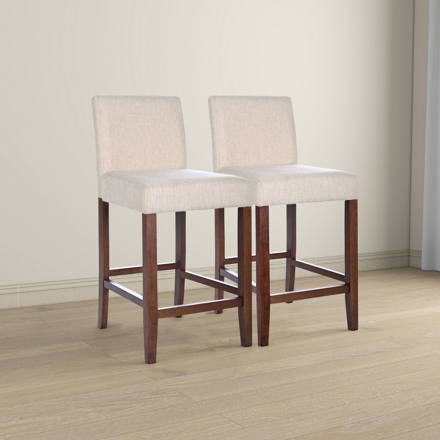 The Dorian Counter Chair (Set of 2) in beige features upholstered seats and backs, dark wooden legs with footrests, and is shown on a light wood floor in a neutral-toned room.