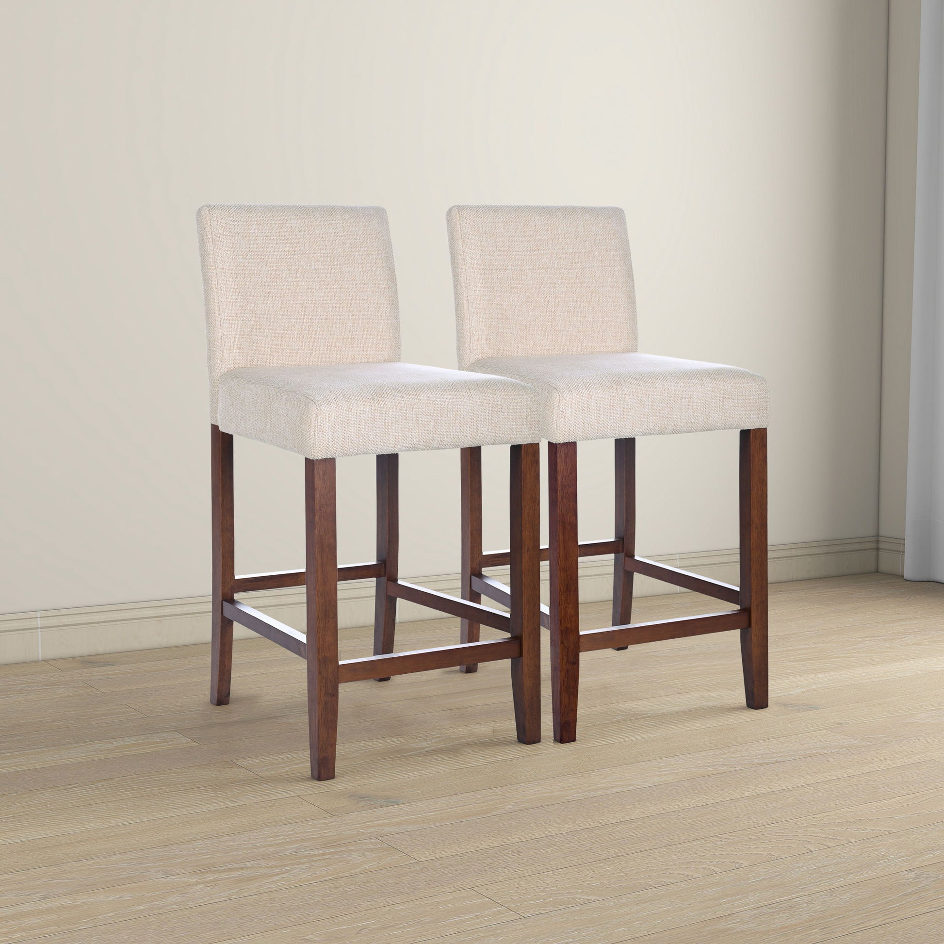 The Dorian Counter Chair (Set of 2) in beige features upholstered seats and backs, dark wooden legs with footrests, and is shown on a light wood floor in a neutral-toned room.