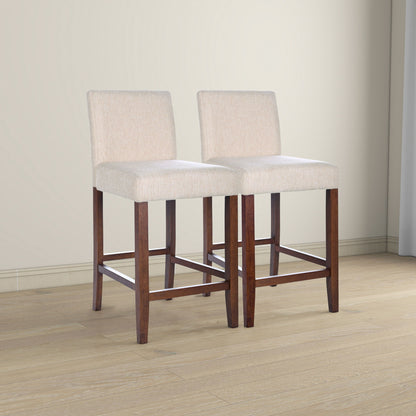 The Dorian Counter Chair (Set of 2) in beige features upholstered seats and backs, dark wooden legs with footrests, and is shown on a light wood floor in a neutral-toned room.