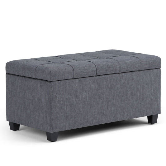 The Sienna Upholstered Storage Ottoman Bench is a rectangular, gray bench with a tufted lid and short black legs, shown on a white background.