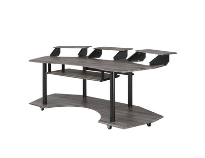 The Eleazar Music Recording Studio Desk features a gray wood finish, curved lower shelf, three raised monitor platforms, sturdy black metal legs, and wheels for easy mobility.