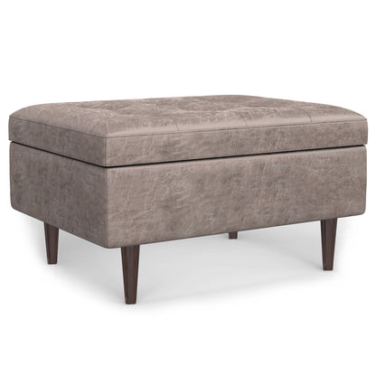 The Shay Large Square Coffee Table Storage Ottoman, mid-century style, features taupe upholstery, a tufted top, and four tapered wooden legs, displayed against a white background.