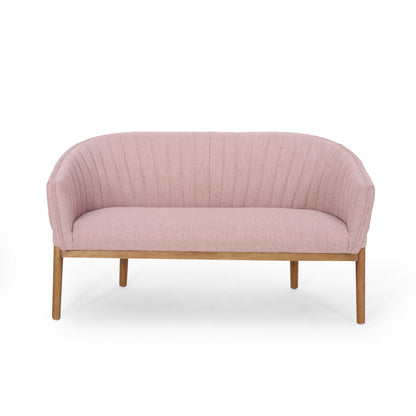 The Mid Century Modern Loveseat features light pink upholstery, a curved channel-stitched backrest, and wooden legs, all set against a plain white background.
