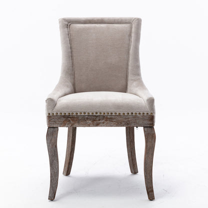 The Ultra Side Dining Chair features thickened beige upholstery, a high backrest, neutrally toned solid wood legs with a distressed finish, and bronze nailhead trim. Set of 2 chairs shown against a plain white background.