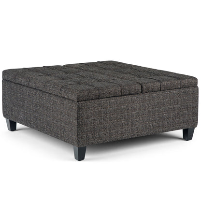 The Harrison Upholstered Coffee Table Storage Ottoman features a square, dark gray tufted top and short black legs, ideal as a coffee table or extra seating.