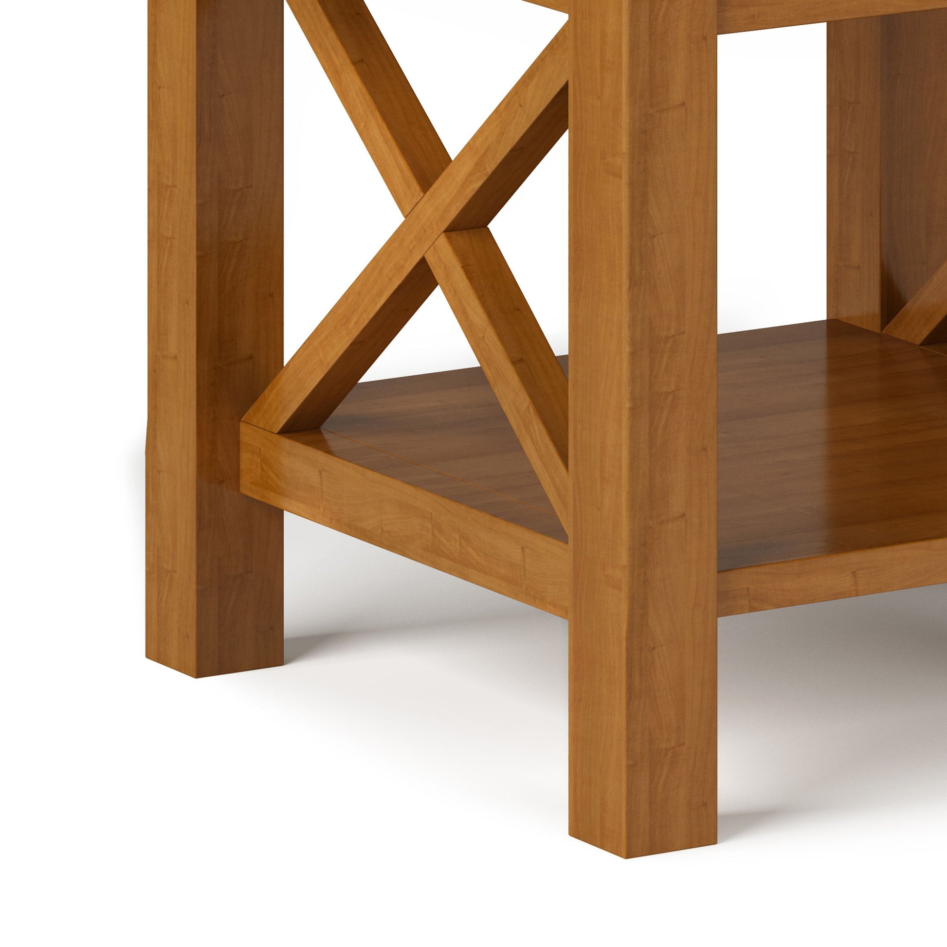 Close-up of the Kitchener - Handcrafted Table shows its square legs, lower shelf, and X-shaped side supports in a medium brown finish, sitting on a white surface.
