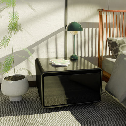 A modern bedroom scene featuring a glossy black Modern Smart Side Table with built-in fridge, wireless charging, USB ports, and induction light, alongside a small green lamp, book, potted plant, crib with brown slats, and bed in natural sunlight.
