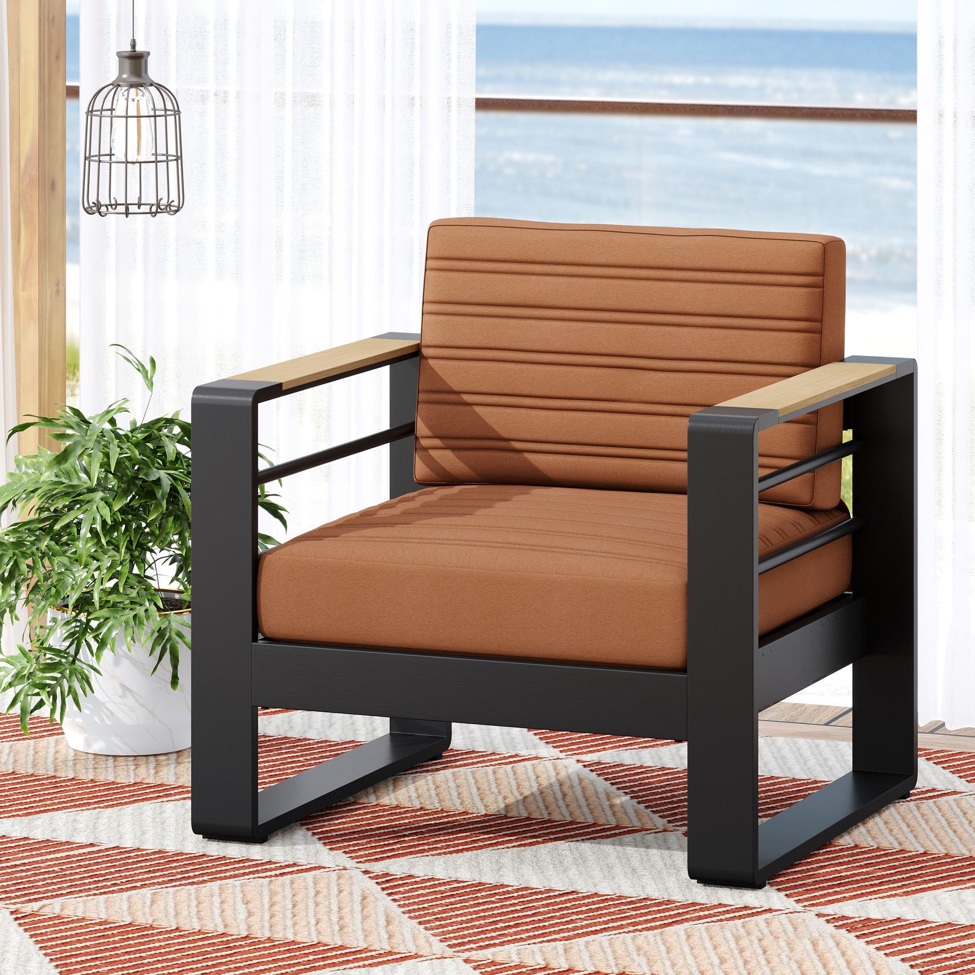 The Giovanna Club Chair Set with aluminum frame features modern brown cushions and sits on a patterned rug beside a green plant, with large windows showcasing an ocean view in the background.