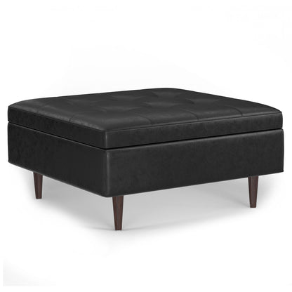The Shay Large Square Coffee Table Storage Ottoman features a black leather button-tufted top and tapered wooden legs, showcasing mid-century style against a plain white background.