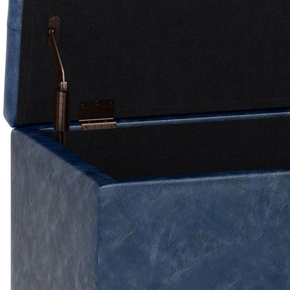 Close-up of the Cosmopolitan - Upholstered Storage Ottoman featuring a blue faux leather exterior and black interior. The opened lid displays an inside corner hinge and support mechanism.