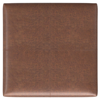 The Gabbie Coffee Table Upholstered Storage Ottoman is a square brown leather piece with stitched lines on top, dividing the surface into four equal sections.