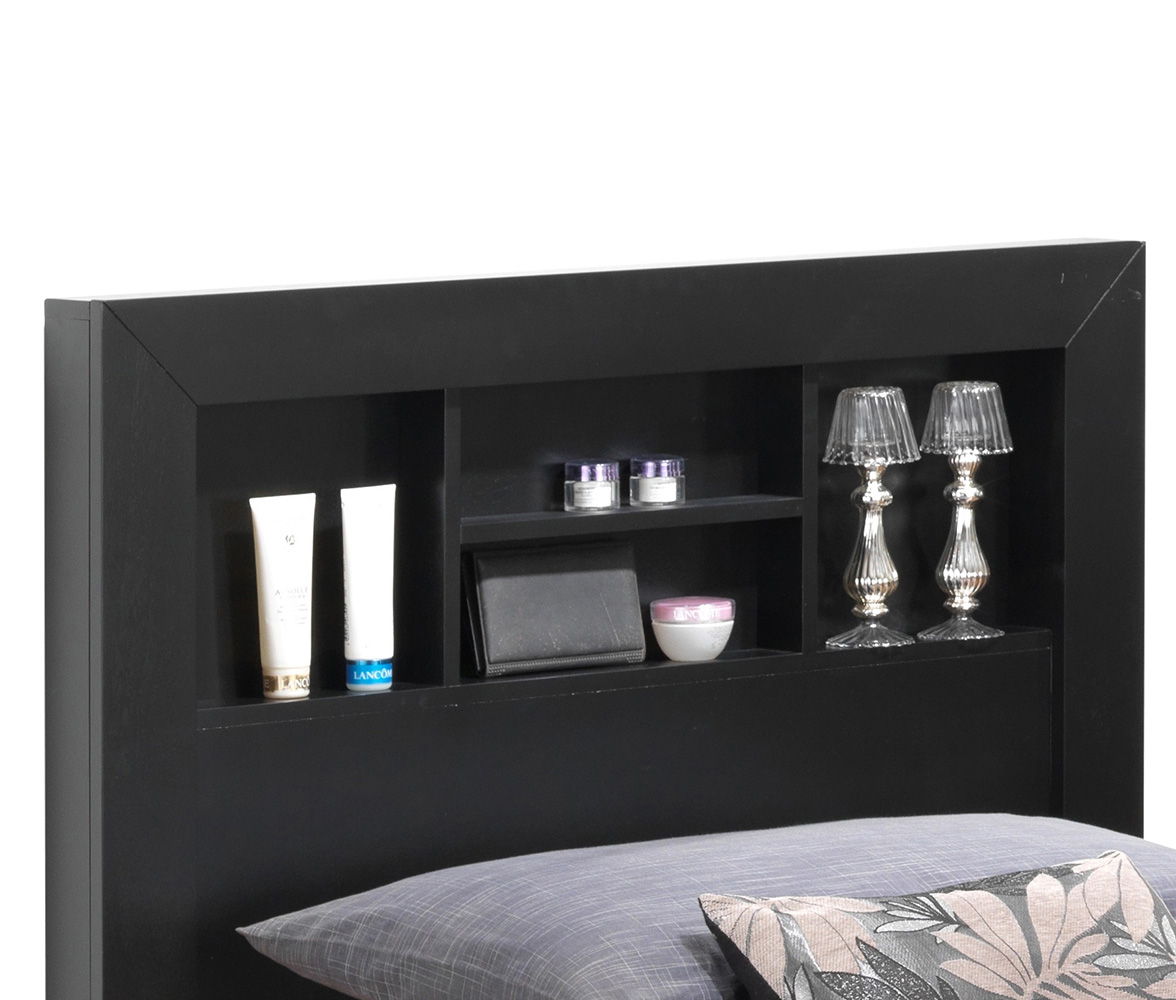 The Bed With Transitional Design Stylish features a black headboard with built-in shelves for toiletries, small jars, a wallet, silver decorative lamps, and a bowl, set above bedding with a gray pillow and floral cushion.