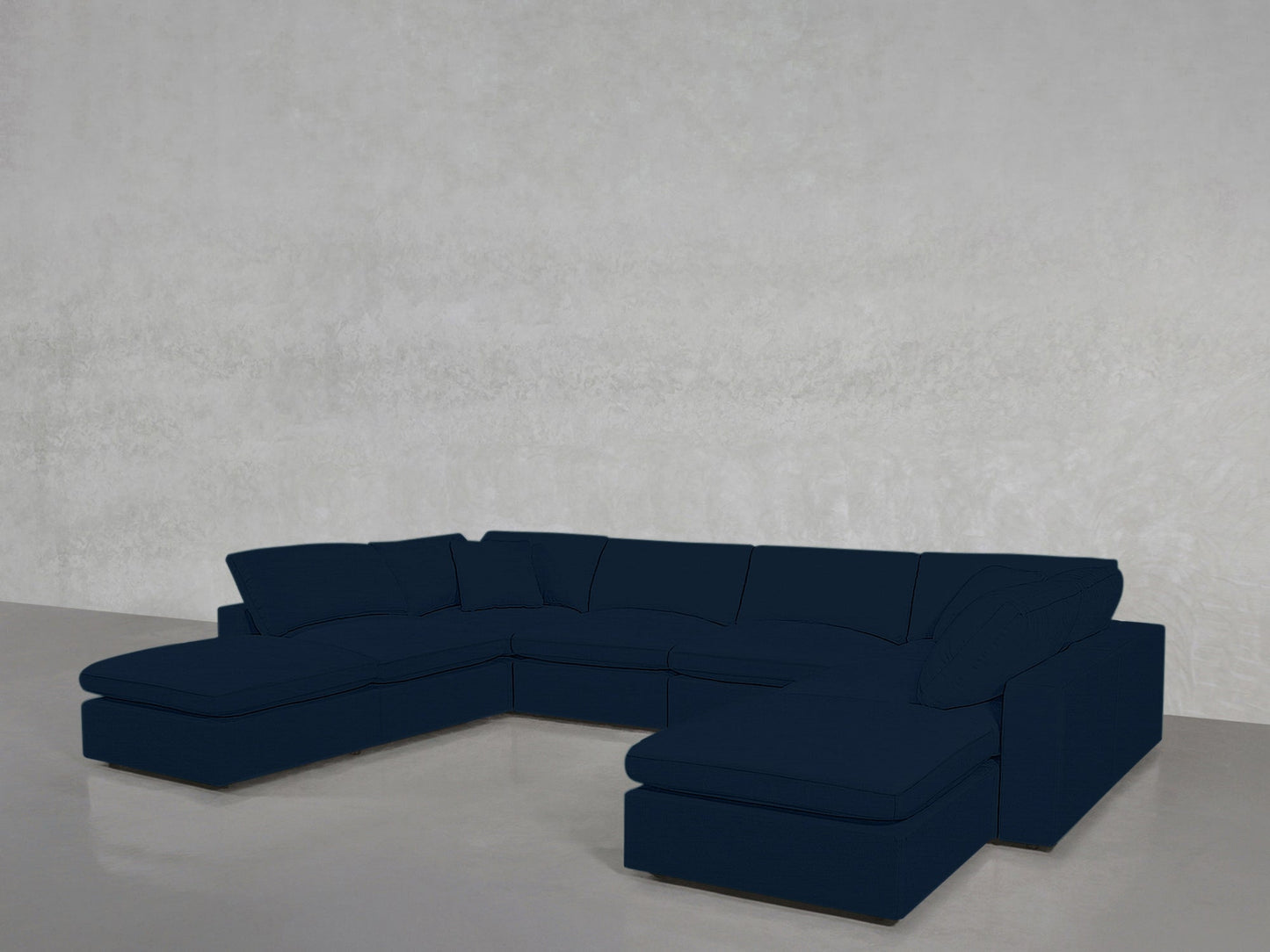 An 8-Seat Modular Double Lounger U-Sectional in dark blue with cushions sits in a minimalist room featuring light gray walls and a polished concrete floor.