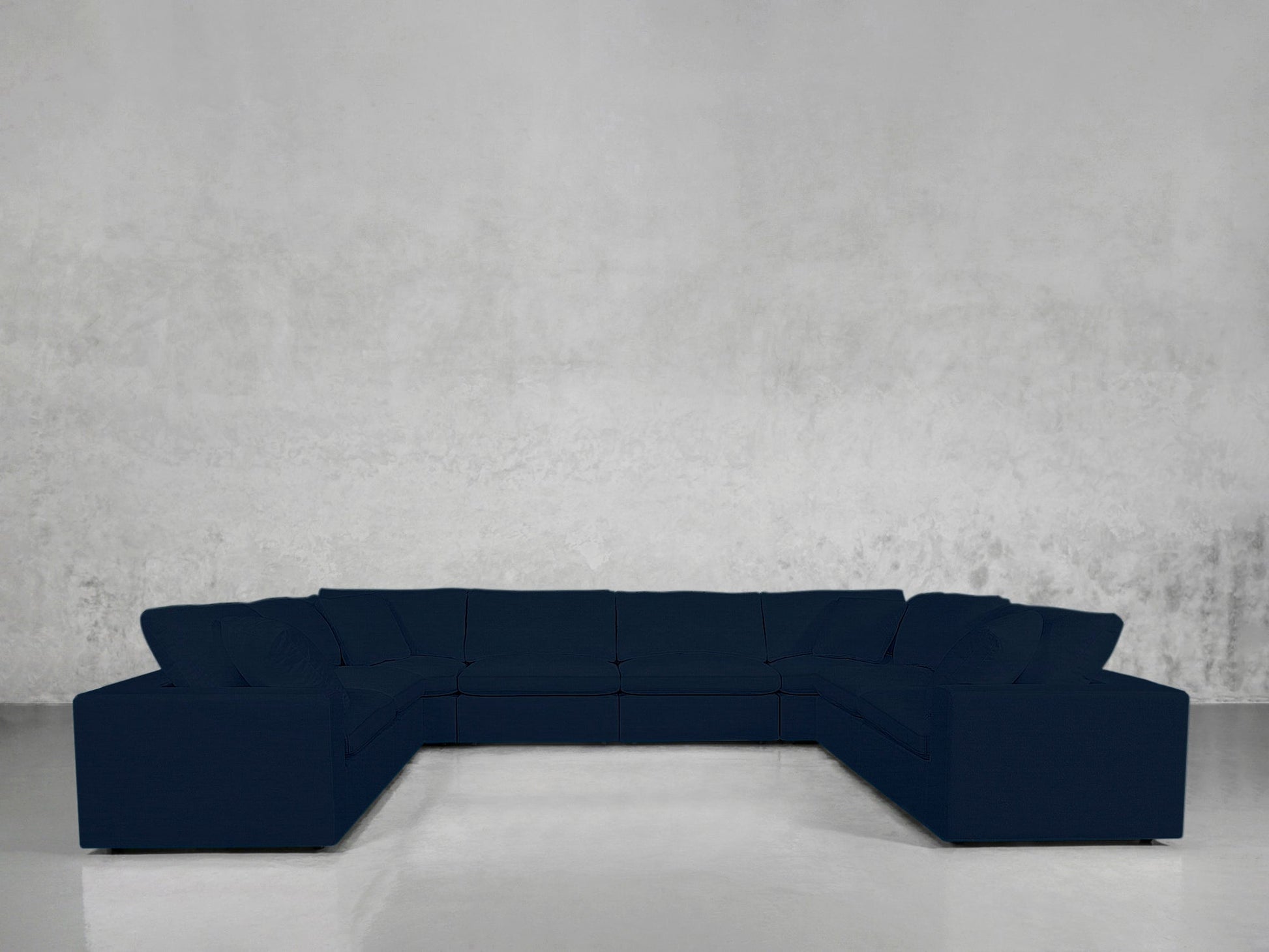 An 8-Seat Modular U-Sectional in dark blue is placed in an empty room with light gray textured walls and a shiny, light-colored floor.