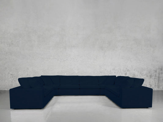 An 8-Seat Modular U-Sectional in dark blue is placed in an empty room with light gray textured walls and a shiny, light-colored floor.