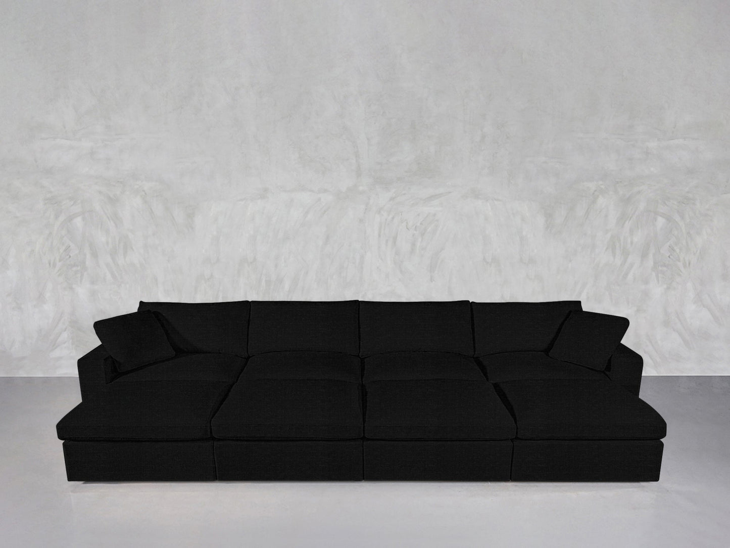An 8-Seat Modular Daybed in modern black is set against a light gray textured wall in a minimalist room featuring a smooth, light-colored floor.