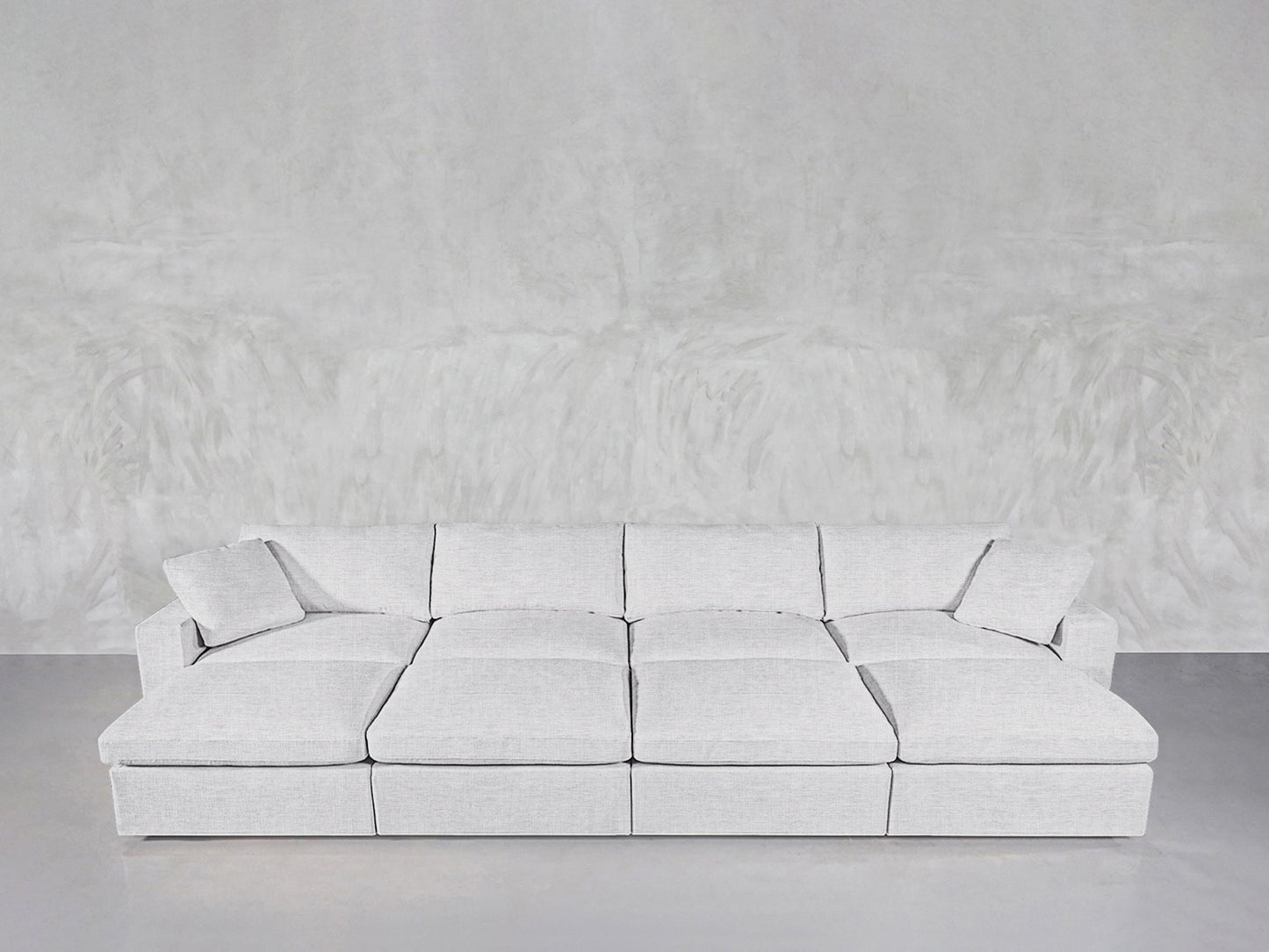An 8-Seat Modular Daybed with a modern, minimalist design in light gray rests against a textured light gray wall on a smooth floor.